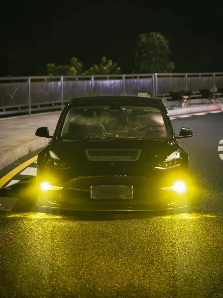 Black Tesla with an upgraded fog lights car kit installed, fog lights switched on at night to improve low-visibility visibility and road awareness.