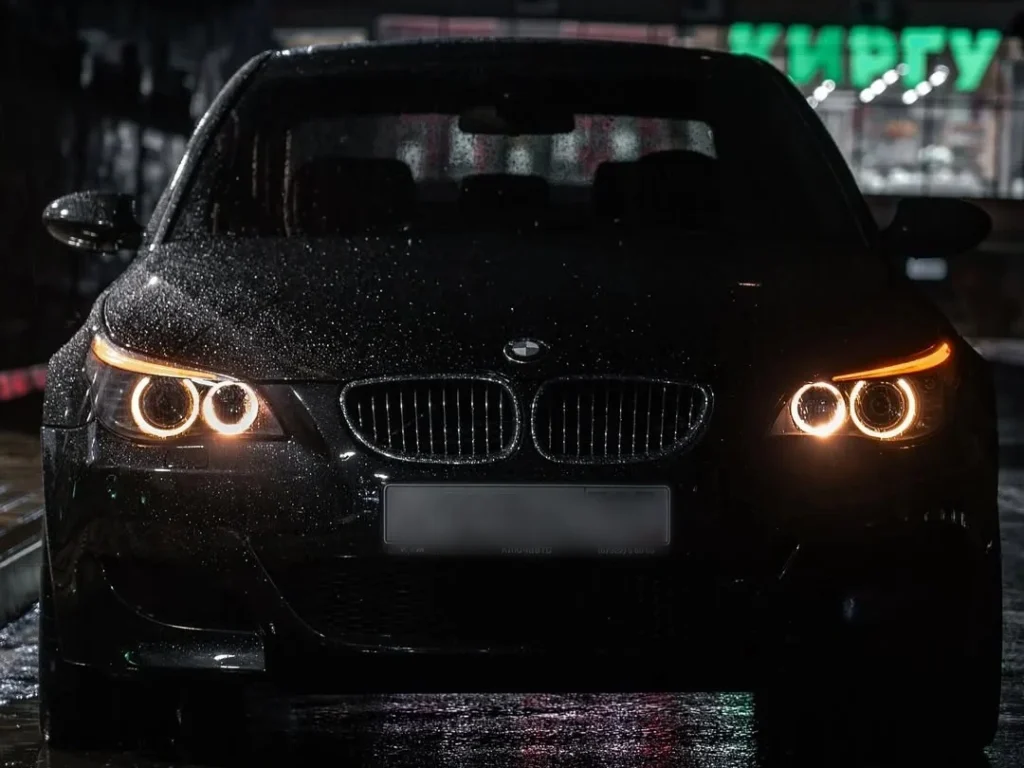 BMW angel eye projector headlights glowing in the rain at night