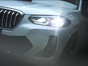 Night road view of a BMW using LED projector headlamps, showing a sharp low-beam cutoff and even beam pattern.