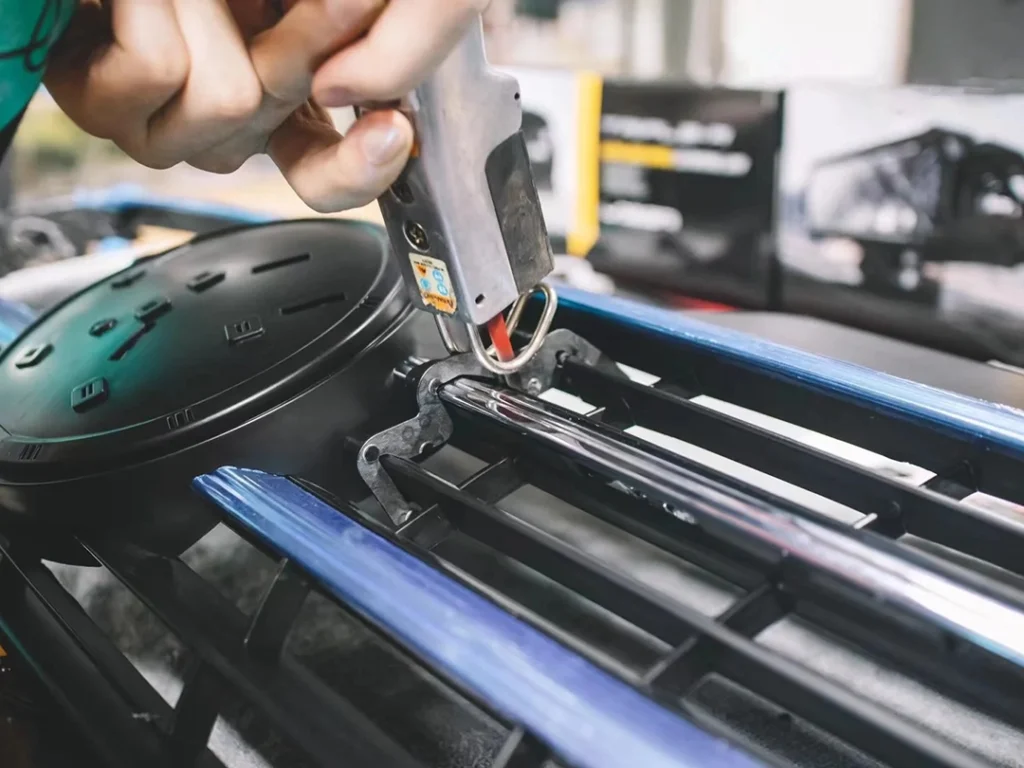 Installer fastening a mounting bracket for LED grill lights behind a vehicle grille.