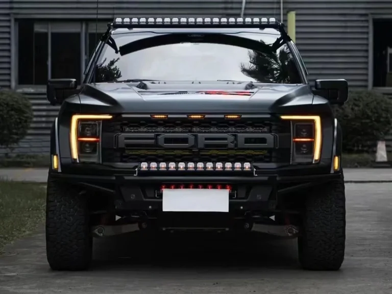 Ford Raptor outside a custom shop featuring amber and white LED Grill lights, plus matching fog lights and spotlights on the front end.