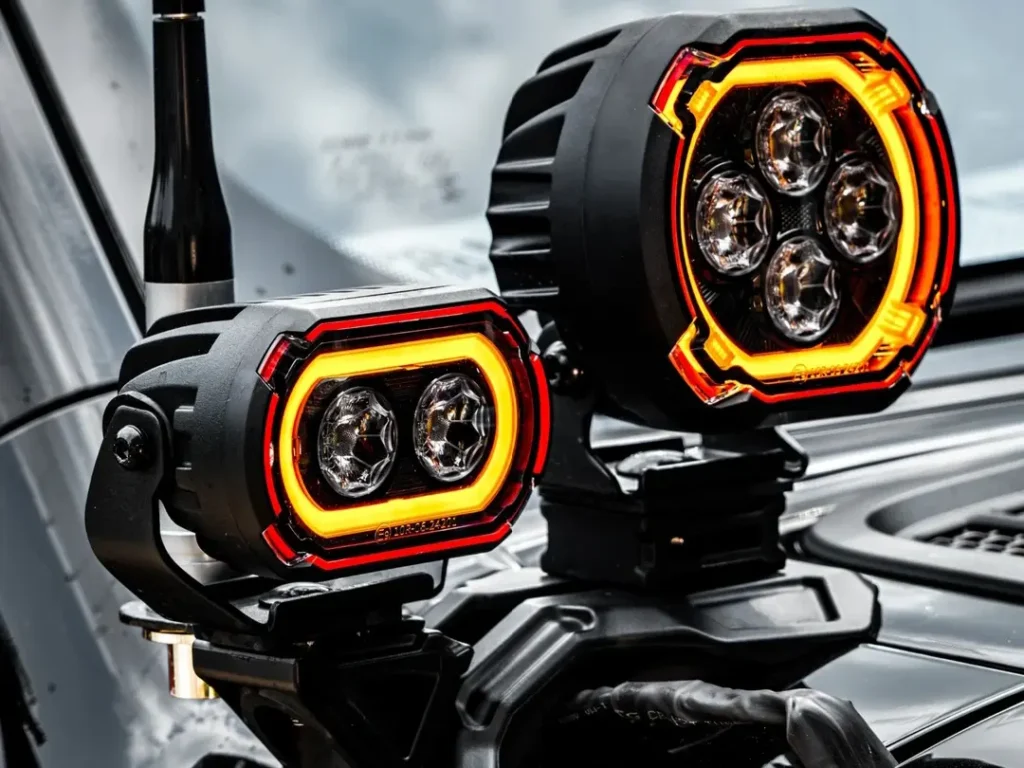 Close-up of two LED car spotlights installed on a vehicle, showing both models side by side.