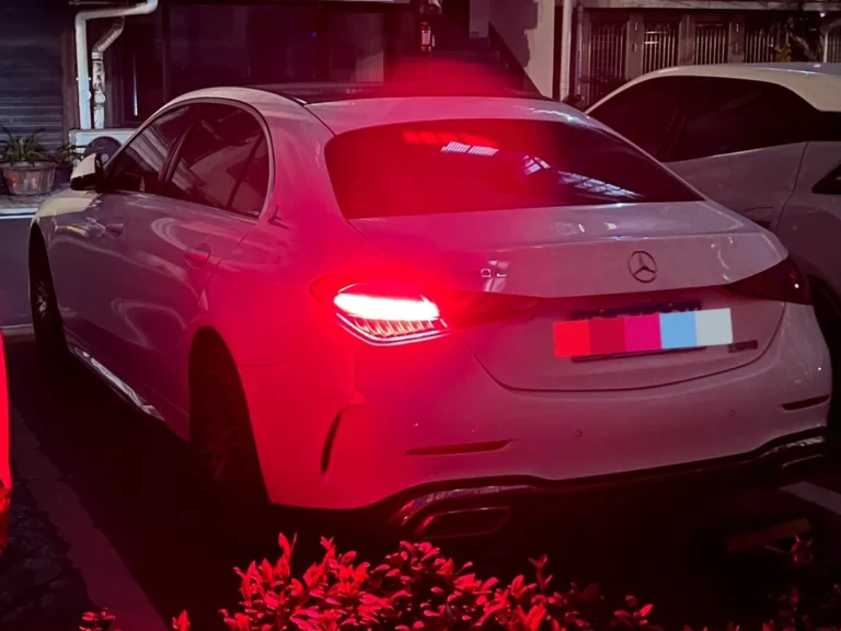 Rear view of a Mercedes C260 in low visibility with one rear fog light illuminated and the other side not lit, illustrating why some cars use a single rear fog lights unit and how it can reduce brake-light confusion.