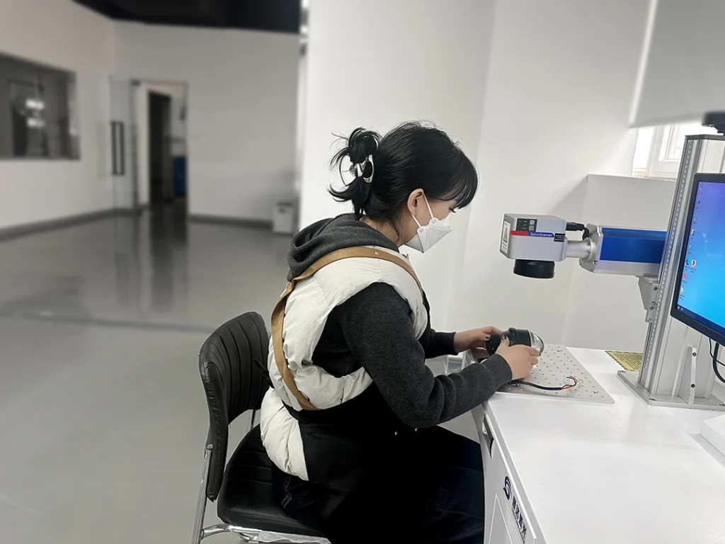 Factory worker inspecting OEM projector headlights during quality control on a production line.