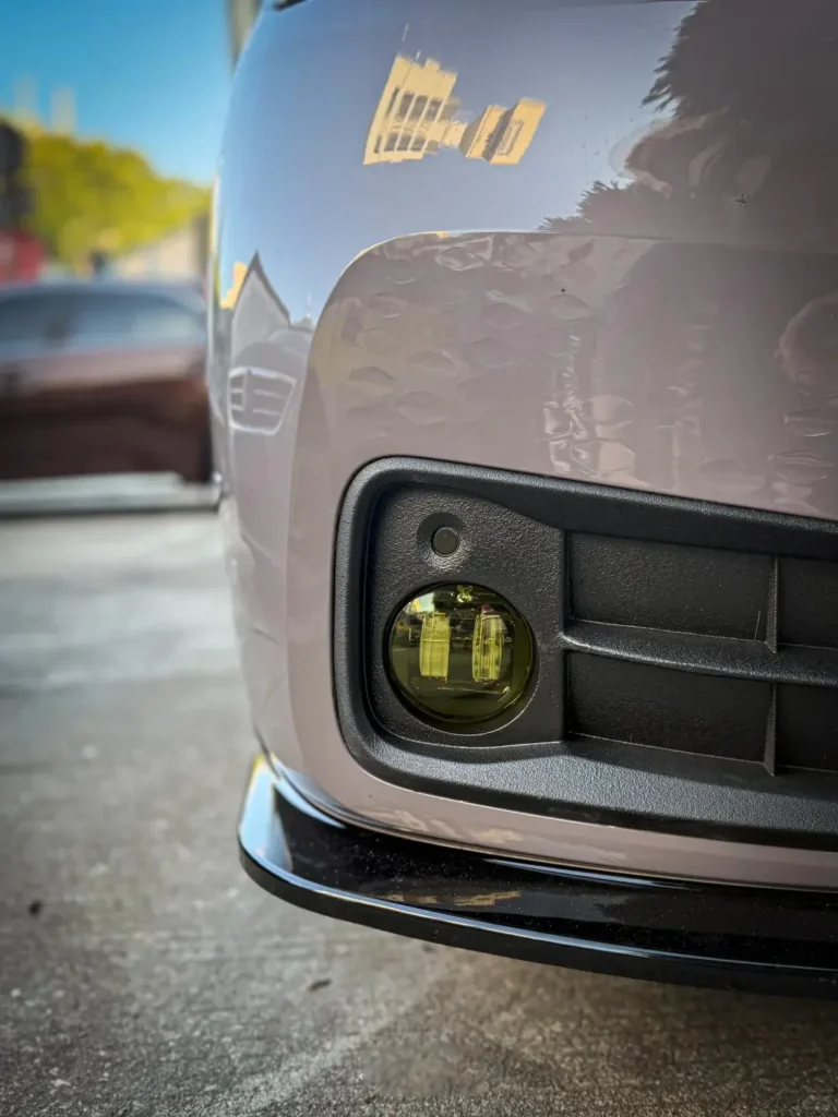 Close-up of a pink sedan with our Fog Lamp Kit installed, showing the fog lamp housing and lens detail.