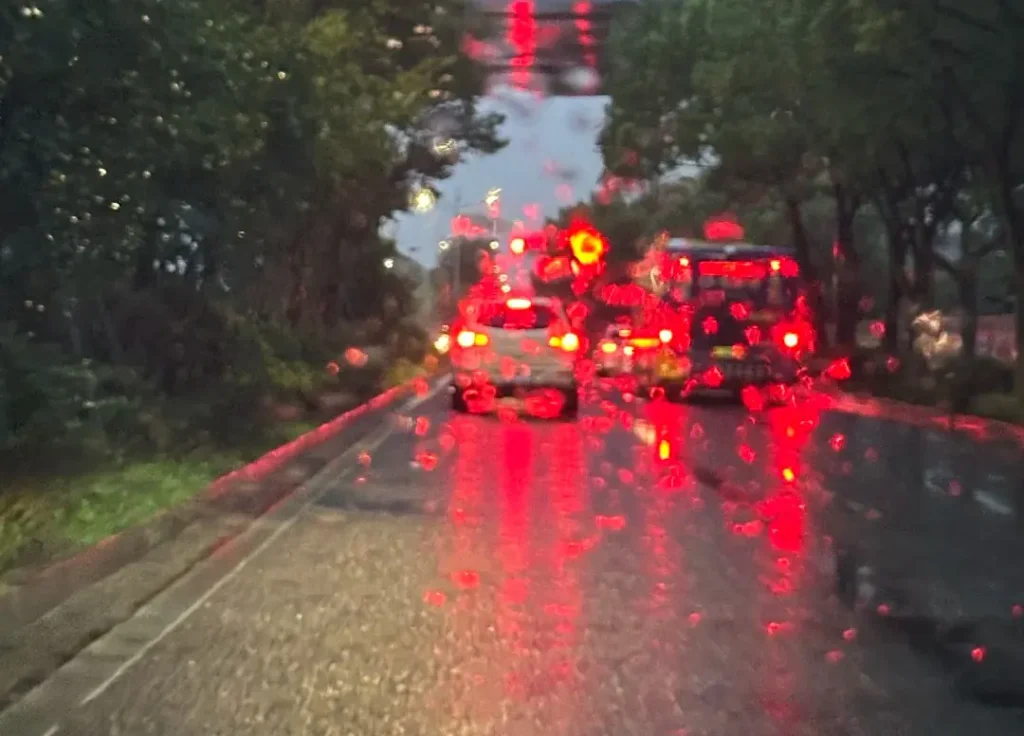 Driver’s view after rain with many cars still using rear fog lights, creating bright red glare and reduced comfort for following drivers.