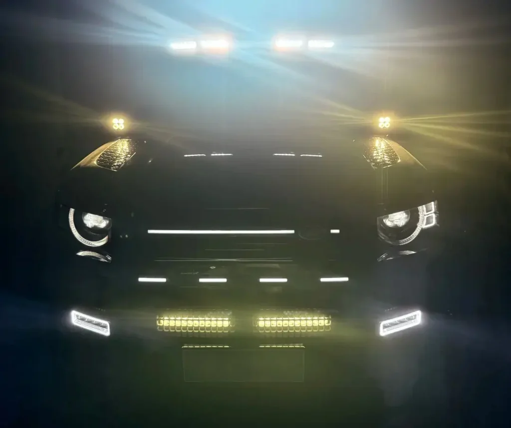 SUV at night with amber car grill lights illuminated alongside headlights, fog lights, and auxiliary driving lights.