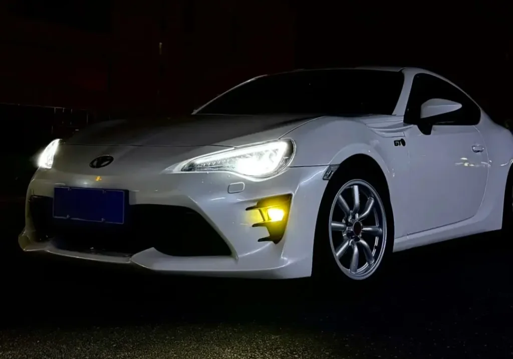 White Toyota sedan at night after fog light upgrade, showing best fog light for car beam pattern and improved road visibility