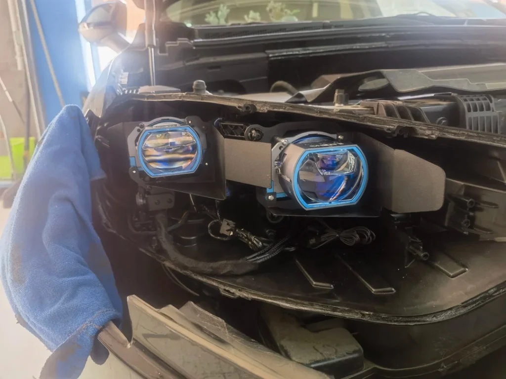 Projector headlight retrofit photo showing a lens installed with the headlight housing cover removed — are projector headlights worth it?