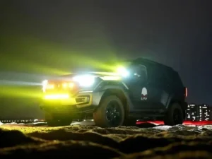 Car spotlights on an SUV lighting a dark rural road at night