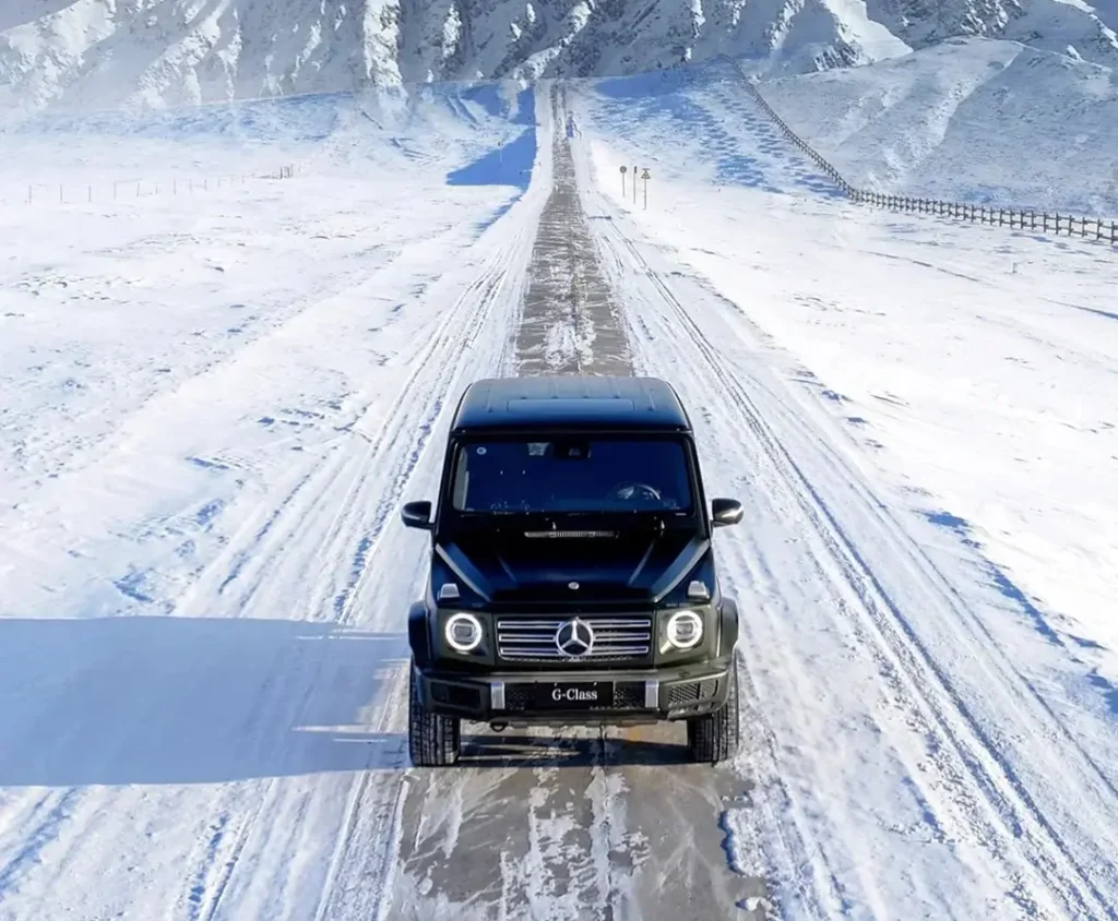 Car driving on icy snowy road showing factory projector headlights in cold conditions