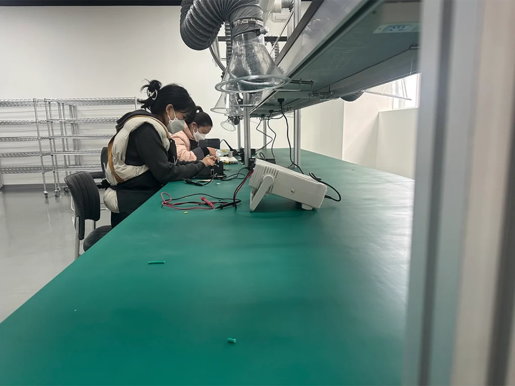 Two workers inspecting assembled factory projector headlights in quality control lab