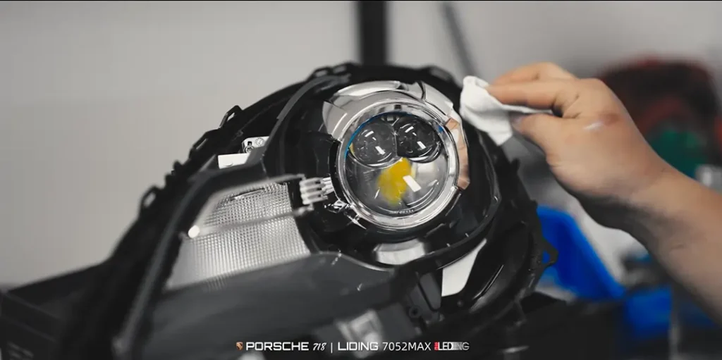 فني يقوم بتركيب مصابيح Leding ثنائية الصمام الثنائي الباعث للضوء LED الأمامية في مبيت المصابيح الأمامية قبل إعادة تجميع السيارة