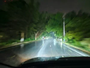 Une voiture roulant par une nuit pluvieuse avec des phares à projecteur éclairant la route loin devant - guide des prix des phares à projecteur.