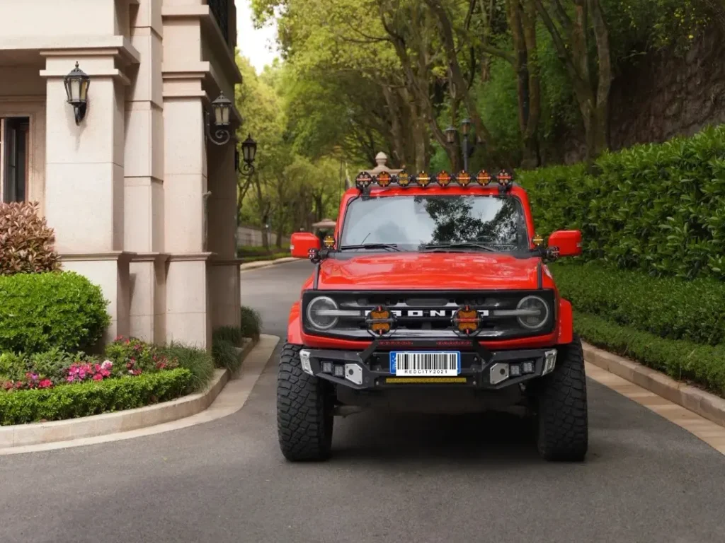 Red SUV parked on a roadside near houses with aftermarket spotlights installed