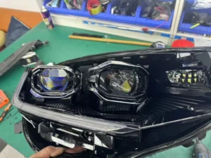 Ensemble de projecteurs bi-xénon de Volkswagen démonté lors d'un remplacement de projecteur, montrant la lentille et le boîtier du projecteur.