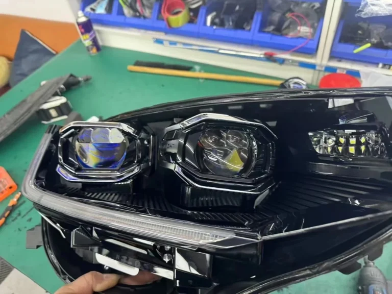 Removed Volkswagen bi-xenon projector headlight assembly during a projector retrofit, showing the projector lens and housing.
