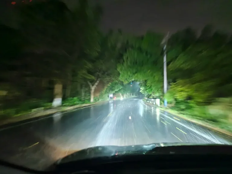 Mobil dengan lampu depan proyektor yang telah ditingkatkan yang menunjukkan visibilitas yang kuat pada malam hujan